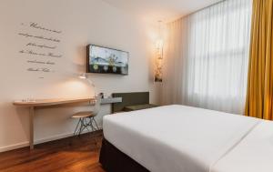 Una habitación de hotel con una cama, un escritorio y una computadora. en Grimms Hotel Hanau, en Hanau am Main