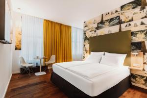 a hotel room with a bed and a table at Grimms Hotel Hanau in Hanau am Main