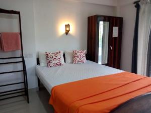 Un dormitorio con una cama con sábanas y almohadas naranjas. en Villa Jungle Paradise, en Unawatuna
