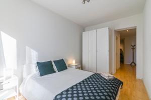 ein weißes Schlafzimmer mit einem großen Bett mit blauen Kissen in der Unterkunft Simplon Residence - Central and Self Check In in Lausanne