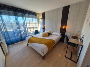 a hotel room with a bed and a large window at Logis Hotel Les Gravades Ussel in Ussel