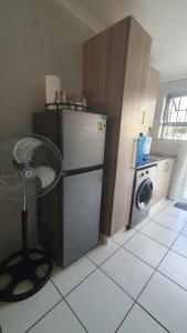 a kitchen with a refrigerator and a washing machine at Sandalion Cottage near OR Tambo Airport & Greenstone in Edenvale
