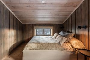 Ce lit se trouve dans un dortoir doté de murs en bois et d'une fenêtre. dans l'établissement Large cabin with spectacular views in Geilo, à Geilo