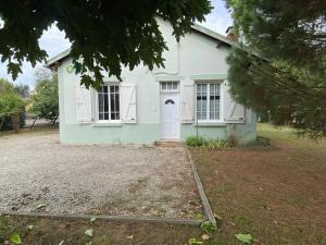 a green house with a white door and a yard at Gîte de Peyrusse in Meauzac