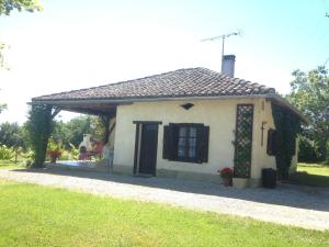 une petite maison blanche avec une porte et une fenêtre noires dans l'établissement Gîte de Raoussou, à Mirabel