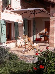 un par de sillas y una sombrilla en un porche en Gîte de Brunenc, en Saint-Vincent-lʼEspinasse
