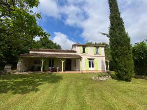 una pequeña casa amarilla con un gran patio en Gîte Borie, en Gasques