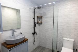 Un baño con lavabo y ducha de cristal. en Hotel - Jodi Lare, 