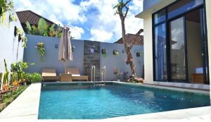 a swimming pool in front of a house with an umbrella at Pondok Murni Mesari in Mantaak