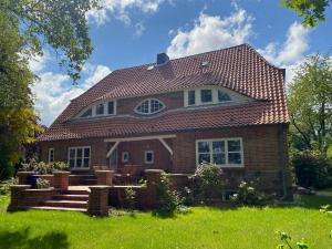 une maison avec un toit rouge sur une cour verte dans l'établissement Stylish Apartment In A Historic Country House, à Meezen