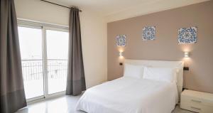 ein Schlafzimmer mit einem weißen Bett und einem großen Fenster in der Unterkunft 4 SPA Hotel in Catania