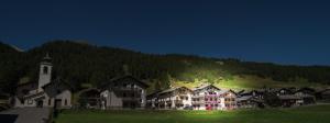 un grand bâtiment en face d'une colline avec une église dans l'établissement Mansardalpina, à Livigno