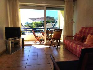 ein Wohnzimmer mit einem Sofa, einem TV und einem Balkon in der Unterkunft Appartement T2 cabine pour 6 personnes avec parking à Vieux-Boucau - FR-1-379-146 in Vieux-Boucau-les-Bains