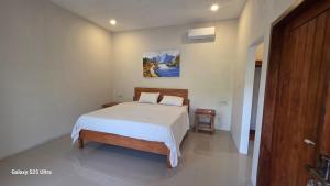 une chambre avec un lit et un tableau au mur dans l'établissement Village Corner Homestay, à Kuta Lombok