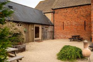 une grange avec une table de pique-nique à côté d'un bâtiment dans l'établissement Shepherds Rest Cotswolds Cottage Farm Stay With Pool, à Lechlade