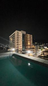 una piscina por la noche con edificios en el fondo en Departamento Orlando, zona centro, en Villa Carlos Paz