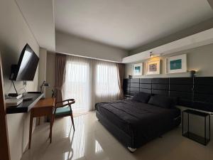 a bedroom with a bed and a desk and a desk at Cozy Bogor Icon Studio Apt bogor W Pool in Kedunghalang