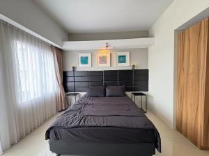 a bedroom with a large bed with a black headboard at Cozy Bogor Icon Studio Apt bogor W Pool in Kedunghalang