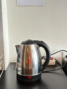 a silver tea kettle sitting on a table at Cozy Bogor Icon Studio Apt bogor W Pool in Kedunghalang +12 photos