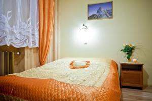 a bedroom with a bed with an orange and white blanket at Smyrecek-centrum Bukowiny in Bukowina Tatrzańska