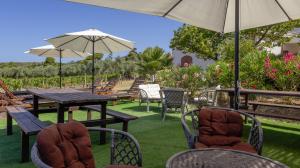 a patio with tables and chairs and an umbrella at SERRA E MESU Affittacamere in Magomadas