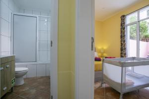 a bathroom with a sink and a toilet and a bedroom at Furnas Cozy Inn in Furnas +78 photos