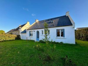 une maison blanche avec un toit noir et une cour dans l'établissement Maison Carnac 4 pièces, jardin, animaux admis - FR-1-377-98, à Carnac