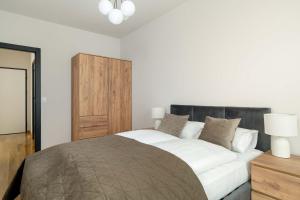 a bedroom with a large bed and a wooden cabinet at Luxury Apartment with Parking & Terrace Remote Work by Renters Prestige in Poznań +18 photos