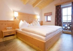 a bedroom with a large white bed with a window at Ferienhaus Wallegg Lodge In Saalbach Hinterglemm in Saalbach Hinterglemm