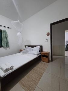 a bedroom with a white bed and a shower at Passadeira Garden in São Tomé