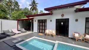 a villa with a swimming pool and a house at Casa Sinabowewa in Ahangama