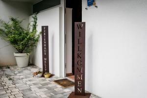ein Schild vor einer Tür mit einem Willkommensschild in der Unterkunft Nette Ferienwohnung in Unterort mit Garten, Terrasse und Grill und Panoramablick in Feistritz ob Bleiburg