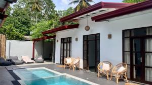 a patio with chairs and a swimming pool next to a house at Casa Sinabowewa in Ahangama