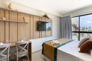a bedroom with a bed and a desk and a tv at Season Smart Flats by BLU stay in Porto De Galinhas +73 photos