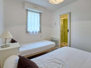 a white bedroom with two beds and a window at T2 cosy, jardinet, animaux admis, parking et WiFi - FR-1-841-35 in Barbotan-les-Thermes