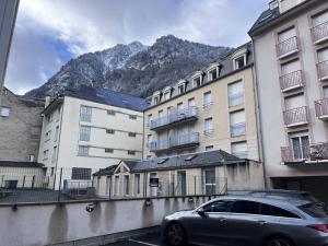 une voiture garée dans un parking en face des bâtiments dans l'établissement Appartement Central avec Parking à Cauterets - FR-1-812-1, à Cauterets