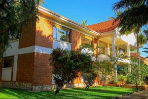 une grande maison en briques avec des arbres devant elle dans l'établissement Calm Suites Kampala, à Kampala