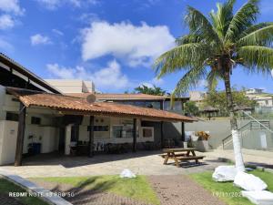 a building with a picnic table and a palm tree at Apartamento São Pedro da Aldeia frente para lagoa in São Pedro da Aldeia