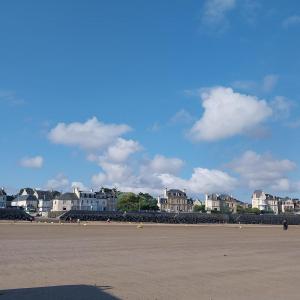 a beach with houses and buildings in the background at Studio De La Mer in Arromanches-les-Bains