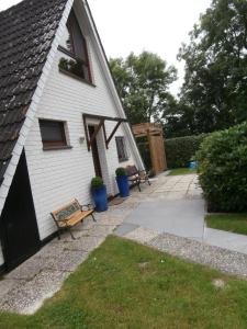 une maison blanche avec un banc dans la cour dans l'établissement Uriges Ferienhaus Mit Garten Und Grill, à Butjadingen