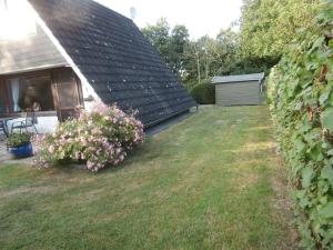 une cour à côté d'une maison avec une haie dans l'établissement Uriges Ferienhaus Mit Garten Und Grill, à Butjadingen