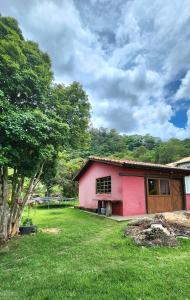 a pink house in a yard with a tree at Chalé Joanópolis - Rancho da Biruta in Joanópolis