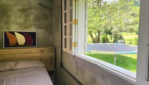 a bedroom with a window looking out at a pool at Chalé Joanópolis - Rancho da Biruta in Joanópolis