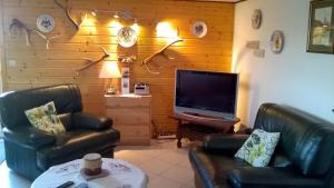 - un salon avec 2 fauteuils en cuir et une télévision à écran plat dans l'établissement Wohnung Du Coucou In Lichtenberg, à Lichtenberg