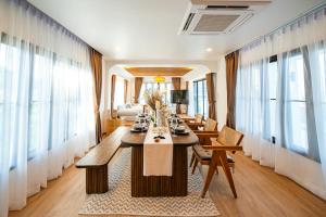 una sala da pranzo con tavoli, sedie e finestre di Phu Talae Villa Rawai Beach a Ban Klang