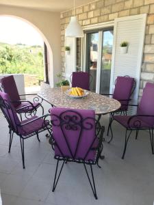 a table with purple chairs on a patio at Gemütliches Haus In Drvenik Mali Mit Meerblick in Dolići