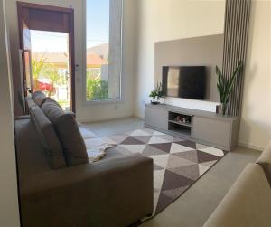 un soggiorno con divano e TV a schermo piatto di Casa a 100 metros do mar a Capão da Canoa