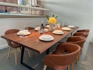 une grande table en bois avec des chaises et une bouteille de vin dans l'établissement Riversdale Retreat - w. beach & golf course access, à Mollymook
