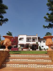 a white building with two large pots on the stairs at Hacienda in Moya