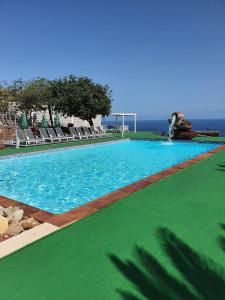a large swimming pool with chairs and the ocean at Hacienda in Moya